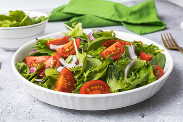 Summer green salad in white bowl plate on grey table