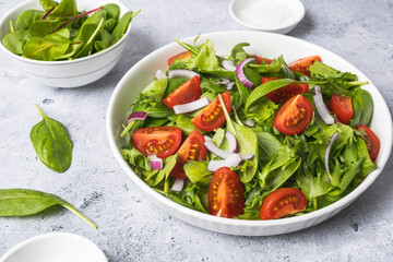 Summer green salad in white bowl plate on grey table