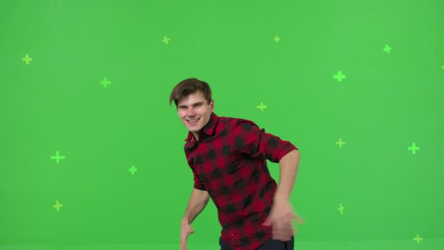 Close-up of young man dancing on a green screen background. Guy makes a gesture with her hands as if swipping the page to the side . Chroma key