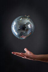 A disco ball levitating above a man's hand, old school party concept