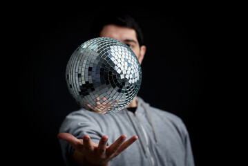 A disco ball levitating above a man's hand, old school party concept