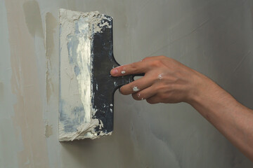 Hand holds construction spatula with putty. trowel with spackling. renovation process