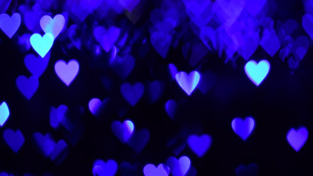 4K UHD video background for Valentine's Day. Border with bokeh of romantic shining blue hearts on a dark background. Love, bokeh in the shape of a heart. High quality 4k video.