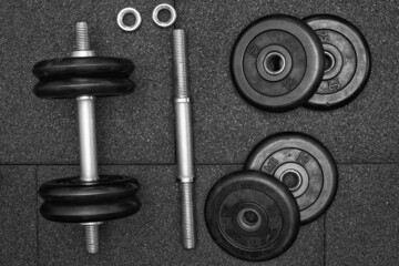 Obraz na płótnie Canvas dumbbell and iron plates on the rubber floor in the gym, Flat lay, black and white photography. Bodybuilding equipment. Fitness or bodybuilding concept background.