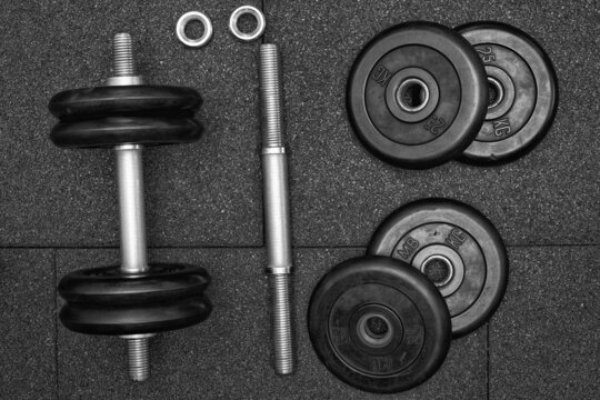 dumbbell and iron plates on the rubber floor in the gym, Flat lay, black and white photography. Bodybuilding equipment. Fitness or bodybuilding concept background.