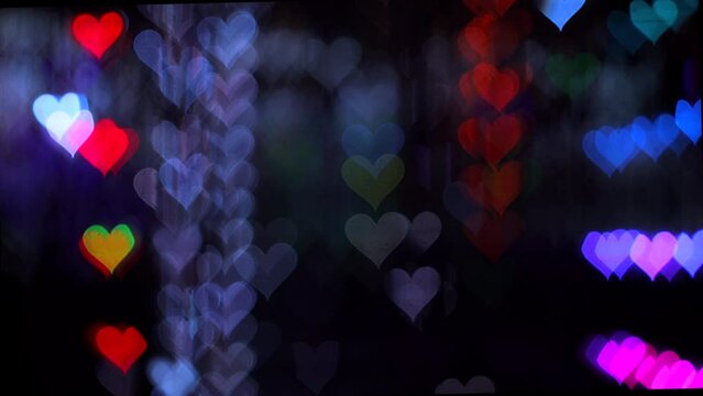4K UHD video background for Valentine's Day. Border with bokeh of romantic shining and shimmering hearts a dark gray background. Love, bokeh in the shape of a heart. High quality 4k video.