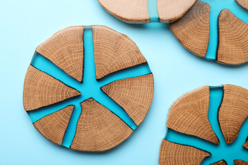 Stylish wooden cup coasters on light blue background, flat lay