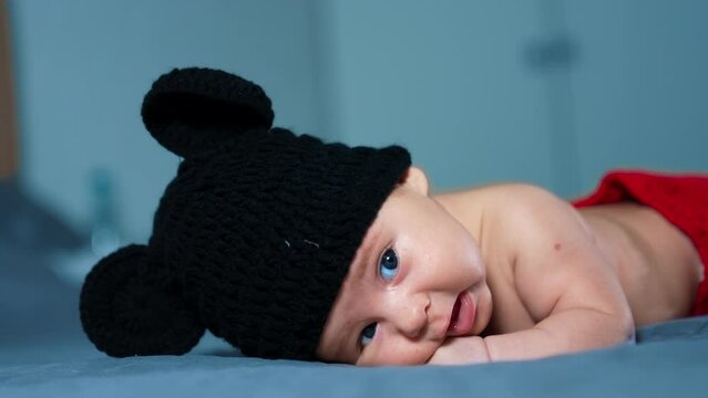 Sweet baby in adorable Mickey Mouse costume. Funny lovely newborn kid lying on his belly. Close up. Blurred background.