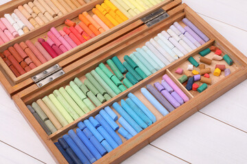 Set of soft pastels in box on white wooden table. Drawing material