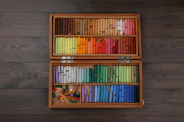 Drawing pastel set in box on wooden background, top view