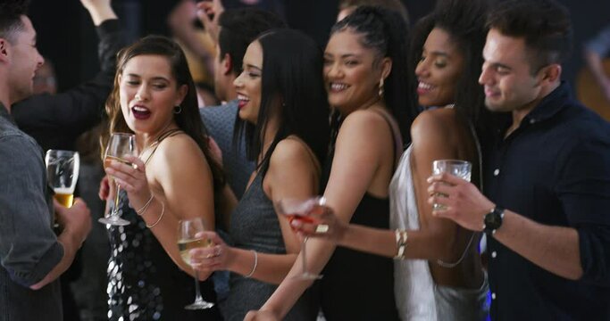 The party scene is in full swing. Young people dancing together at a party. Happy diverse group of friends drinking and having fun in a nightclub. Enjoying a live music performance event together