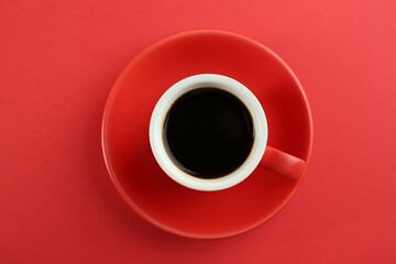 Obraz na płótnie Canvas Cup of tasty coffee on red background, top view