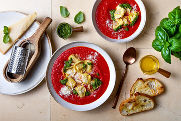 Homemade Italian tomato or roasted pepper soup with tortellini, pesto and parmesan cheese. Top view