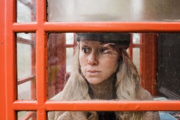 woman looking through an English telephone box on a cold day