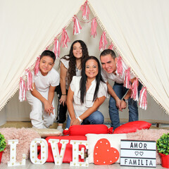 Hispanic parents and children show love under a teepee with a sign that says 