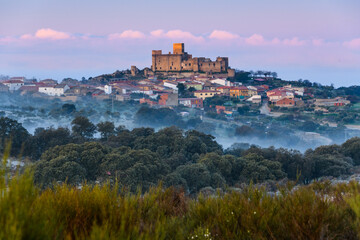 Obraz na płótnie Canvas Sun rises over the castle and the village of Belvís de Monroy, Spain