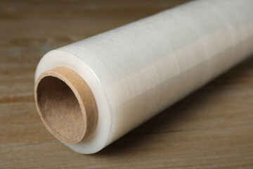 Roll of plastic stretch wrap film on wooden table, closeup