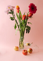 The concept of heart-shaped apple cakes sprinkled with powdered sugar, apples and vase with flowers  on a soft pink background