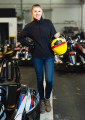Portrait of nice woman holding helmet at kart circuit
