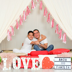 Hispanic dad and son show love under a teepee with a sign that says 