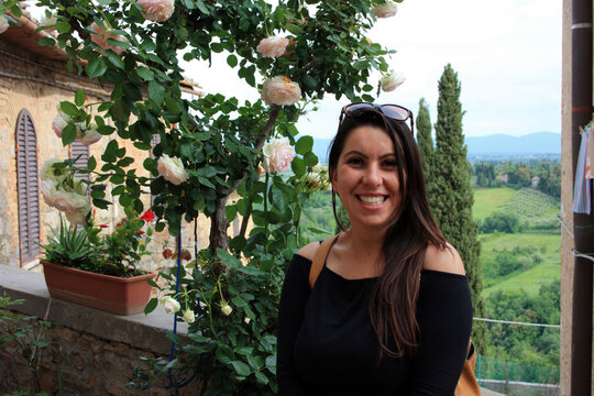romantic girl next to a rose garden of light roses on vacation in the countryside among the Tuscan valleys