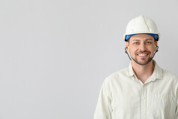 Handsome man in hardhat with ear plugs on light background