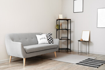 Shelf unit with decor, sofa and blank photo frames in light room