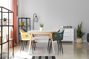 Interior of modern dining room with stylish table, chairs and shelf units