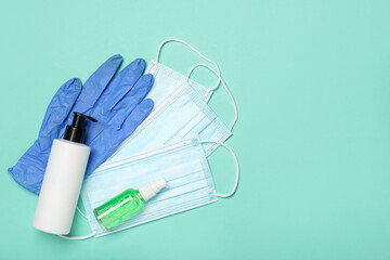 Medical masks, rubber gloves, soap and hand sanitizer on color background