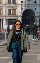 Fototapeta premium woman walking in the city, wearing sunglasses and a stylish outfit.