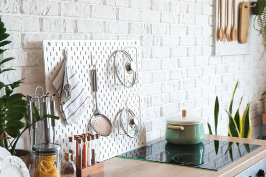 Pegboard with kitchenware on counter near white brick wall