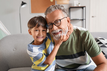 Little boy and his grandfather hugging at home