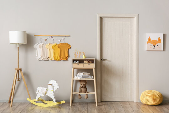 Interior Of Light Children's Room With Baby Bodysuits, Lamp And Table