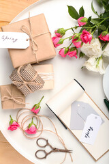 Tray with gift boxes, notebook and roses on wooden background
