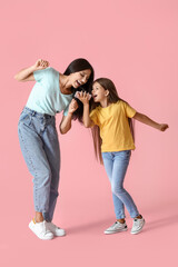 Happy dancing woman and her daughter on color background