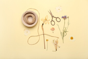 Dried pressed flowers, rope and scissors on beige background