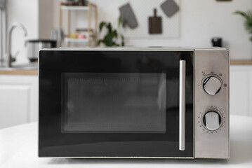 Modern microwave oven on white table in light kitchen