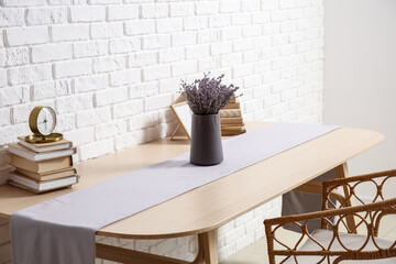 Books, clock and vase with lavender on table in room