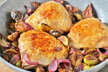 chicken with figs. dish with figs. fried chicken with figs and onions in pan. Soft focus.