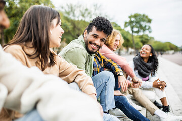 Diverse group of young people laughing together - Hispanic latin man smiling at camera while having fun with multiracial friends in city street - Friendship, unity and millennial colleagues concept - Powered by Adobe