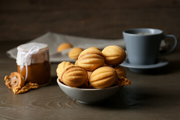 Bowl of tasty walnut shaped cookies with boiled condensed milk on dark wooden table