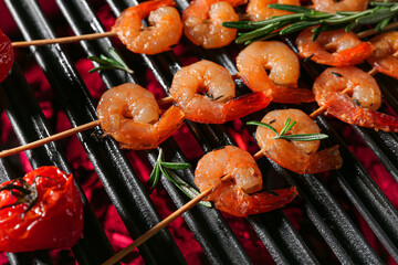 Skewers with delicious shrimps, tomato and rosemary on grill, closeup