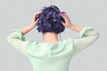 Beautiful young woman with violet hair on light background, back view. Very Peri - color of year...
