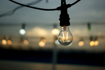photo of a dim light bulb against the backdrop of the sunset sky.