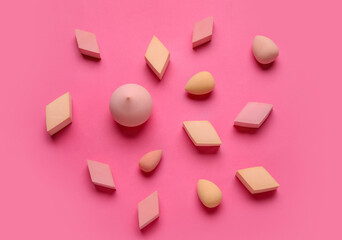 Fototapeta na wymiar Different makeup sponges on pink background