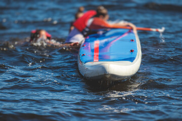 Group of young sup surfers fall from SUP stand up paddle board, women drowning, concept of fail...