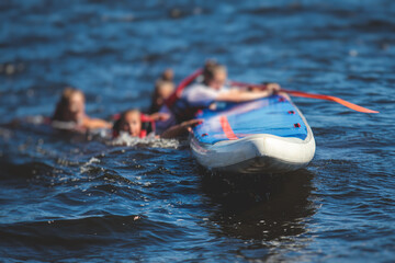 Group of young sup surfers fall from SUP stand up paddle board, women drowning, concept of fail...