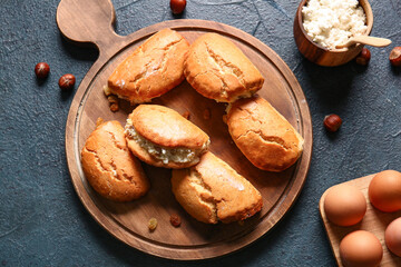 Wooden board of tasty sochniki with cottage cheese on dark background