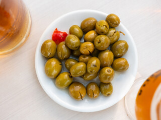 Bunch of green olives served on plate. Appetizer on table.