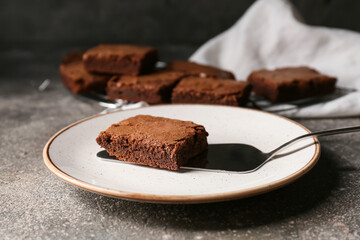Plate with piece of tasty chocolate brownie on grey background